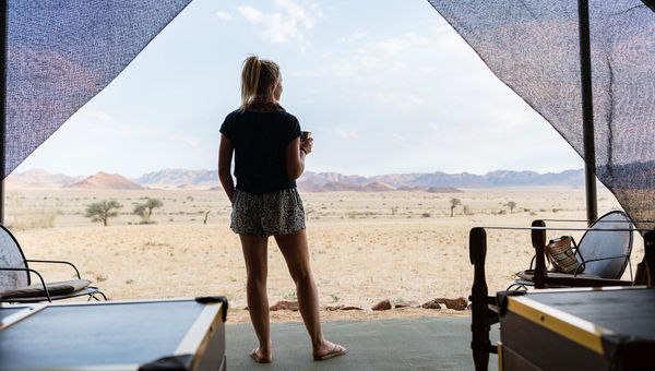 A Geographic Expeditions guest in tent accommodations at Camp Sossus in Namibia.