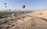 A number of hot air balloons soar over the Nile River Valley and the desert sands of the Valley of the Kings just outside of Luxor, including a number of Viking guests on excursion during a sailing aboard the Viking Aton.