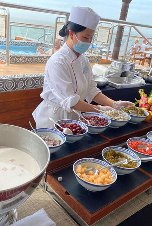 A station serving sweet coconut milk with several accompaniments, such as melon and beans.