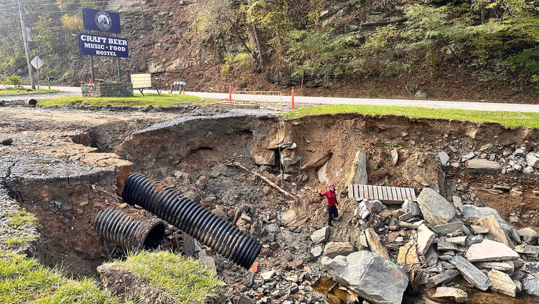 Cruise editor Andrea Zelinski waves from a pit created when Hurricane Helene destroyed part of the parking lot at The Station at 19E, an Appalachian Trail hostel in Roan Mountain, Tenn.