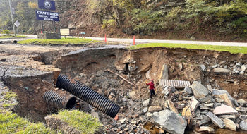 Cruise editor Andrea Zelinski waves from a pit created when Hurricane Helene destroyed part of the parking lot at The Station at 19E, an Appalachian Trail hostel in Roan Mountain, Tenn.