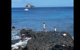 Boys fishing off a rock on Tahuata; the Aranui 5 is in the background.