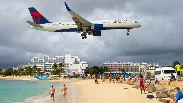 A Delta Boeing 757 flying over Maho Beach before landing at Princess Juliana International Airport in St. Maarten.