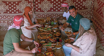 The four-course feast that is part of the Platinum Heritage safari experience is enjoyed in traditional Emirati fashion, at a stout and simple wooden table while sitting on a cushioned, backless chair.