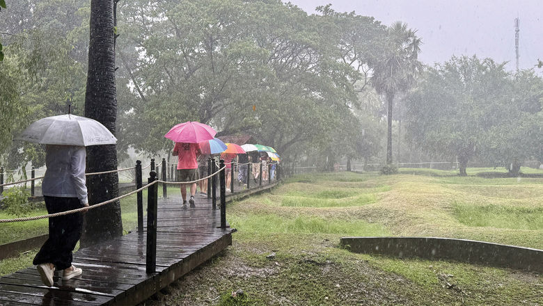 AmaWaterways guests tour Choeung Ek, a killing field in Cambodia outside of Phnom Penh that was once an orchard, in the rain with umbrellas provided by the company.