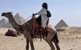 The author rides a camel named Casanova against the backdrop of the Pyramids of Giza while on a press trip with Viking for the Viking Aton.