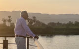 Viking Aton guest takes in the scenic views of sailing on Egypt's Nile River at sunset.